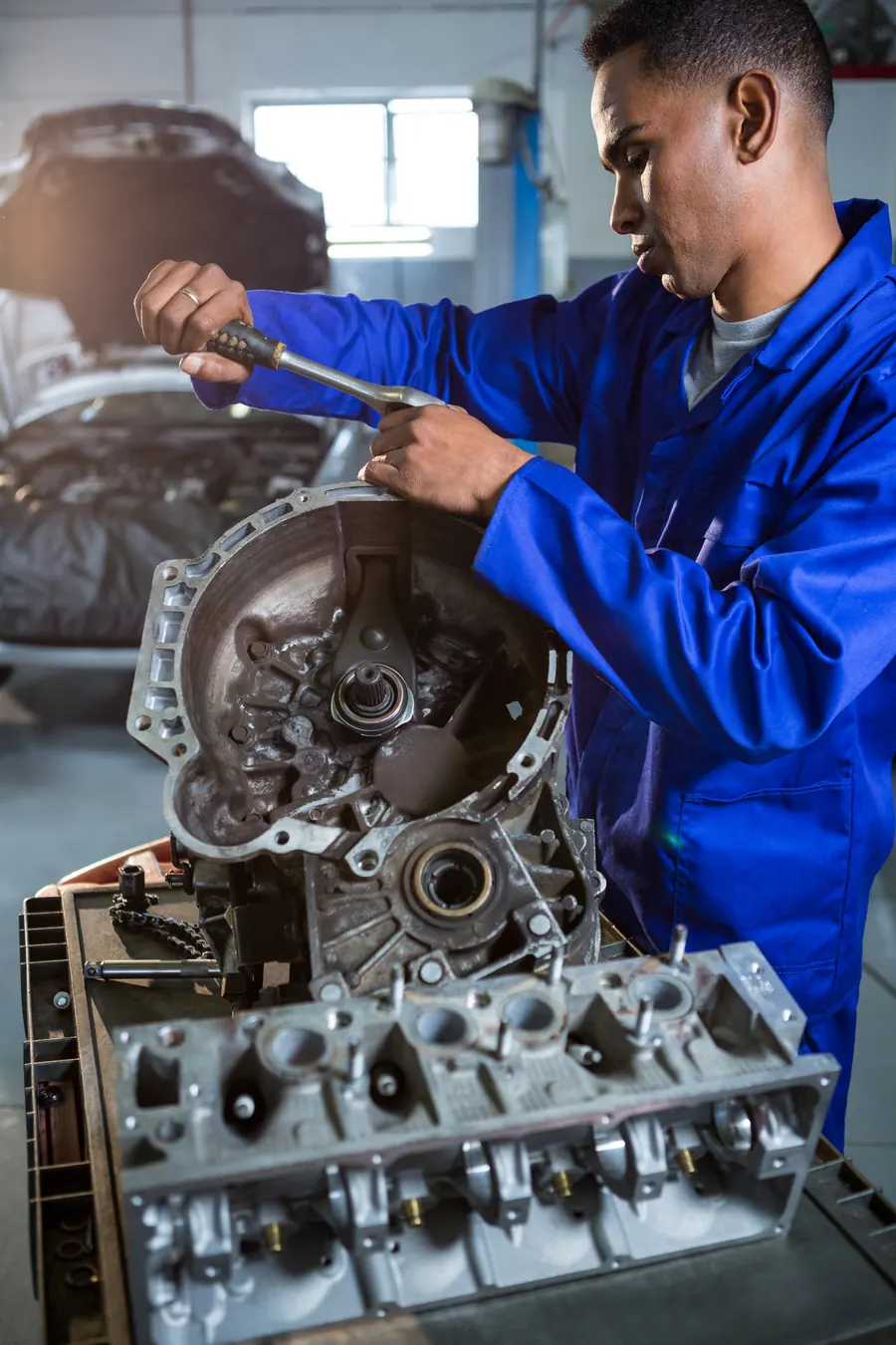 Mechanic repairing an engine part with a ratchet
