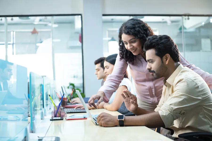 Team collaborating around a laptop in a workspace