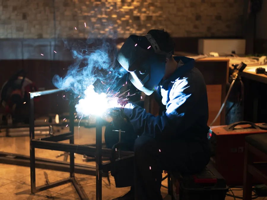 Trainee welding metal with a protective mask in a workshop