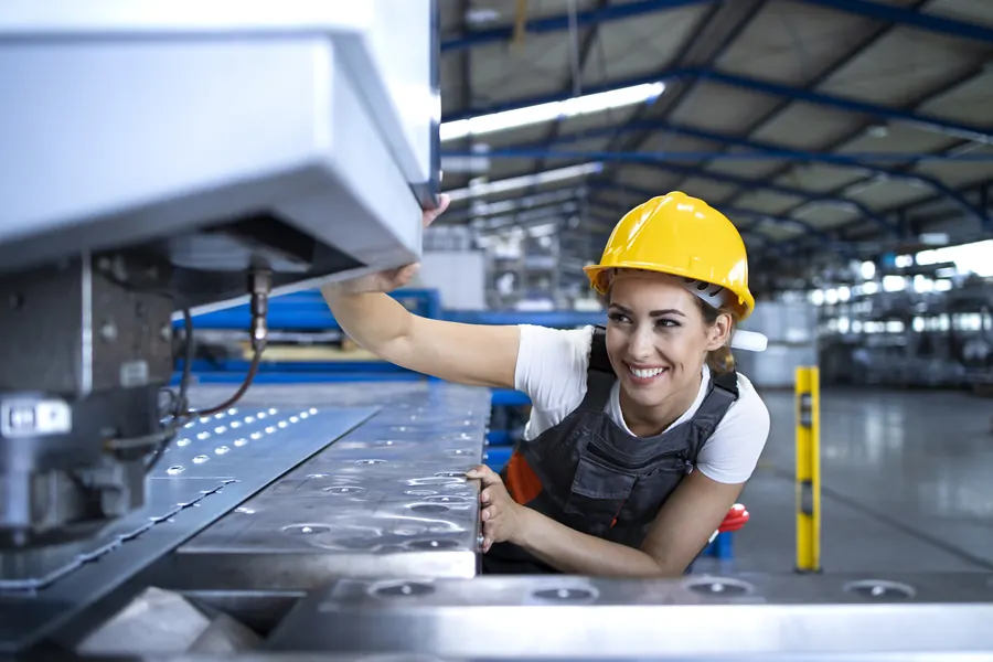 Woman factory worker operating a production line machine